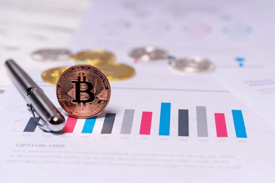Bitcoin on a table next to a pen,