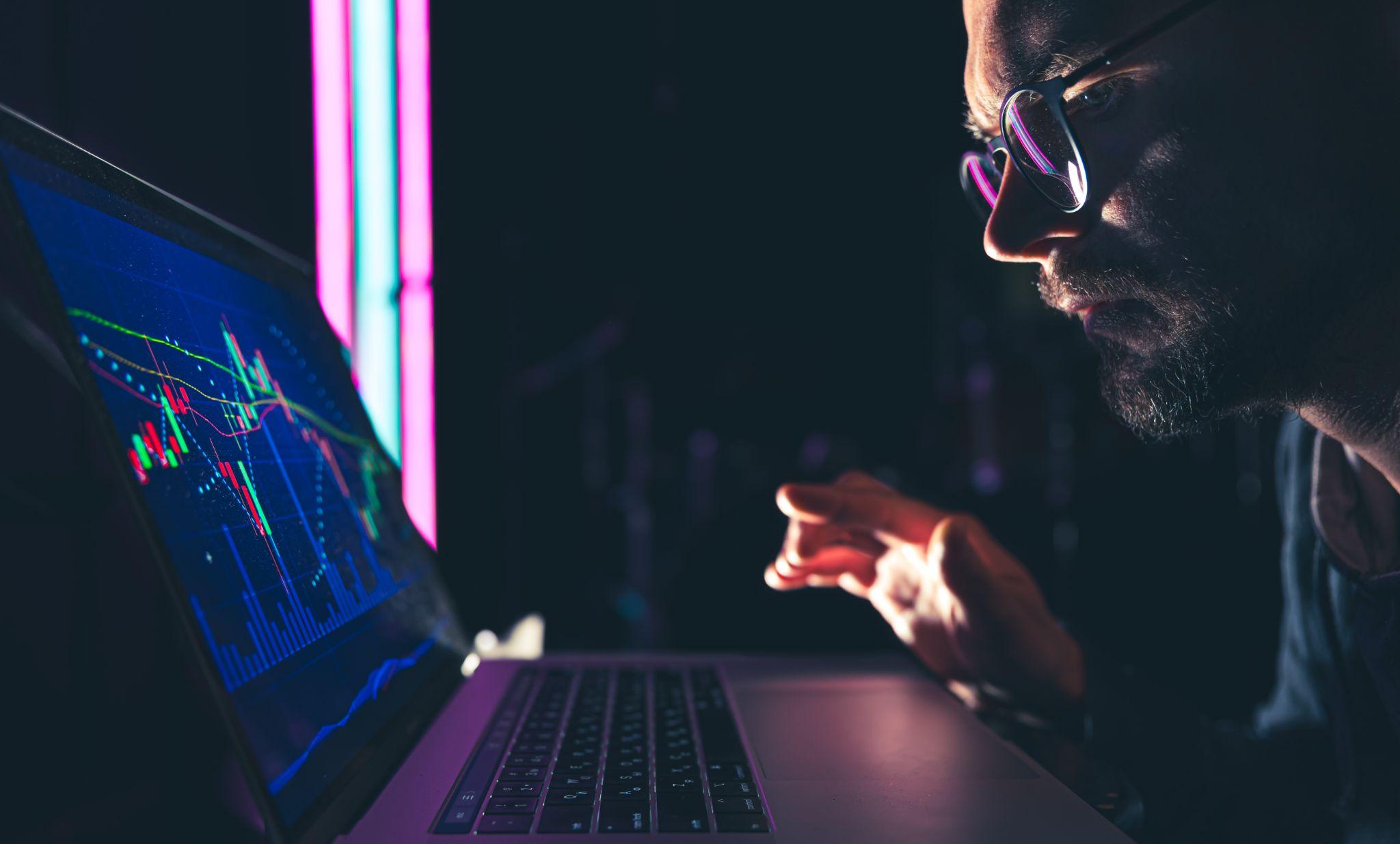 Man in glasses viewing crypto data on a laptop